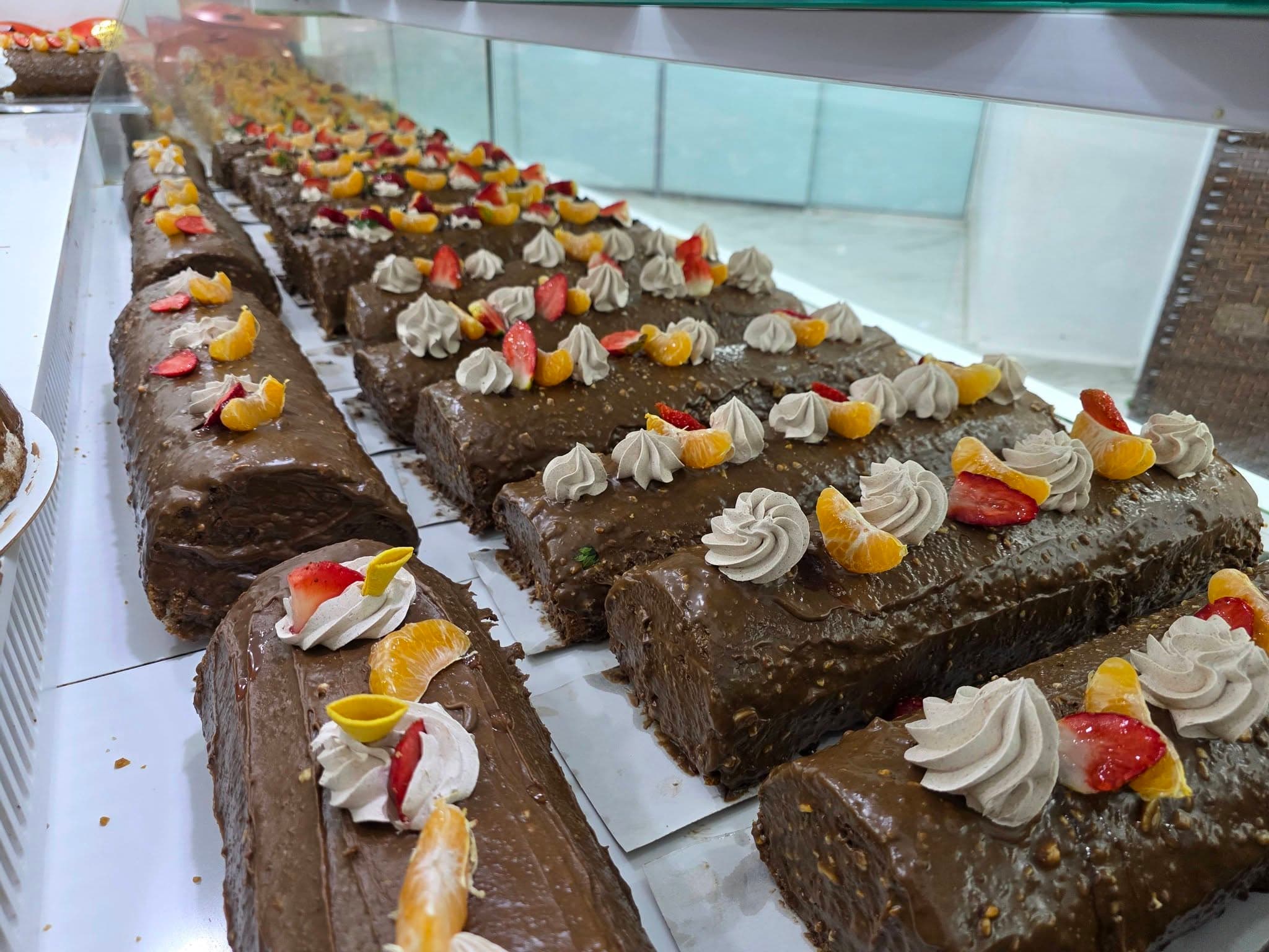Bûches au chocolat alignées en vitrine, décor de fruits confits