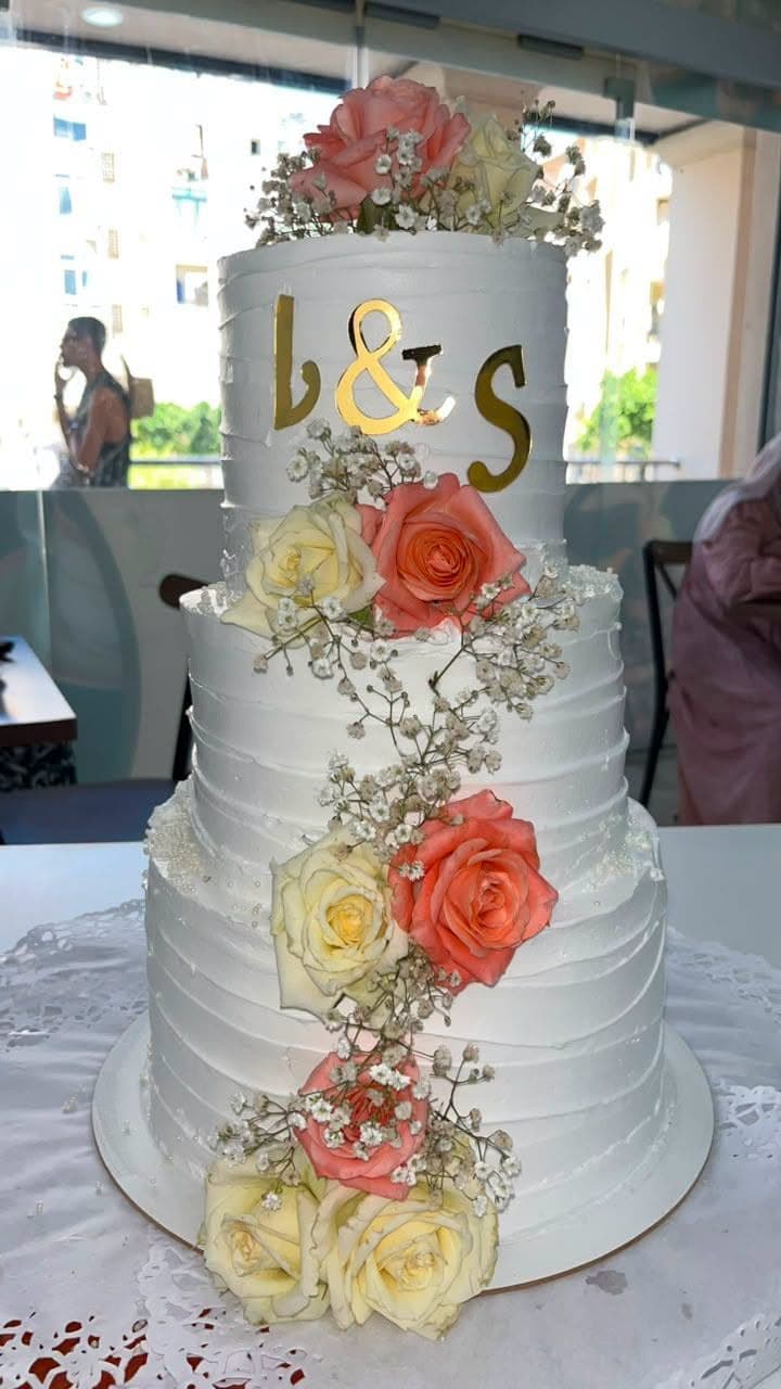 Gâteau de mariage à quatre étages, roses fraîches et initiales dorées