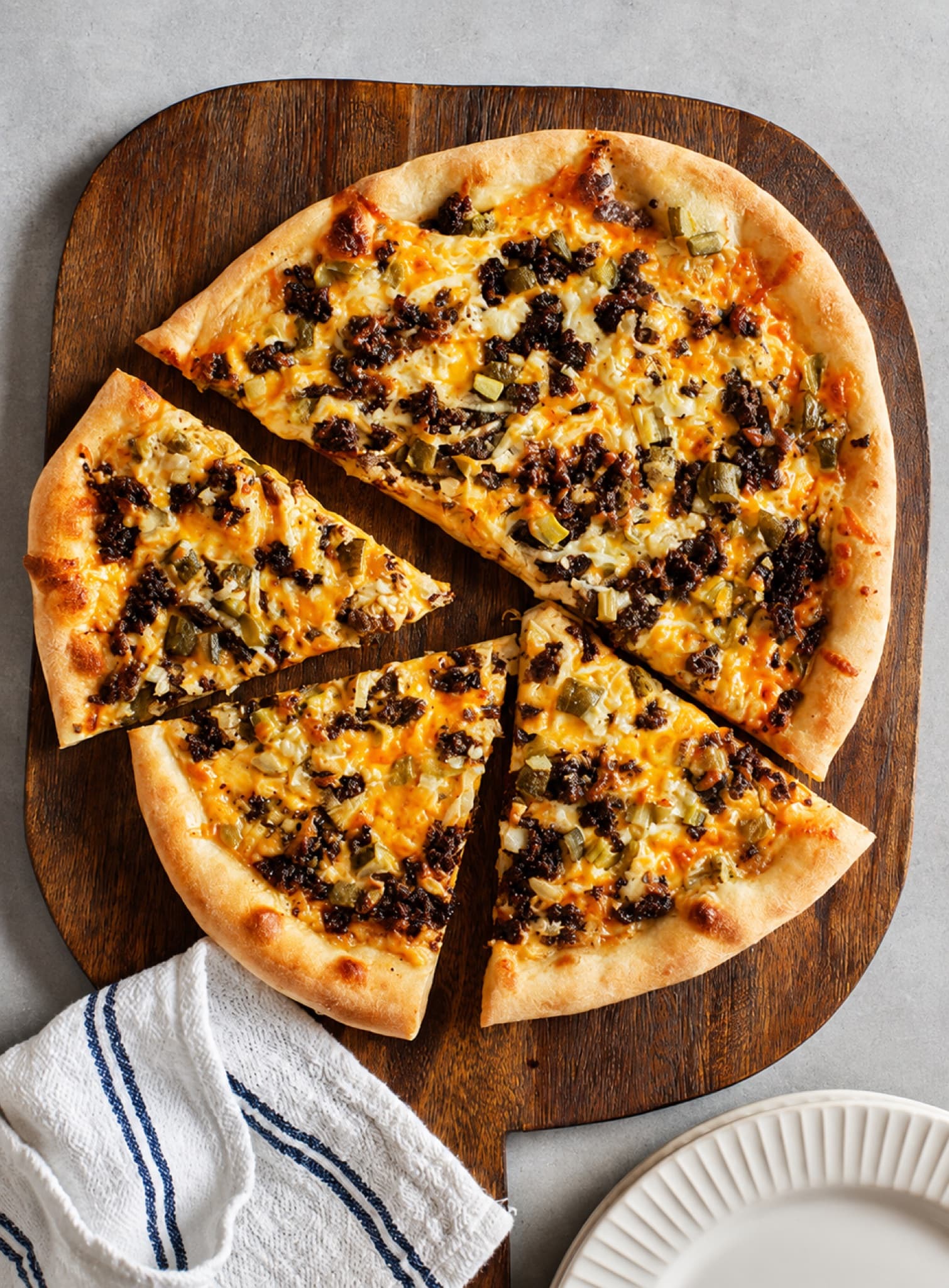 Pizza entière découpée en parts, sur planche de bois